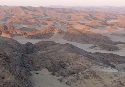 The red rocks of the desert mountains of Namibia gleam under the rising sun.